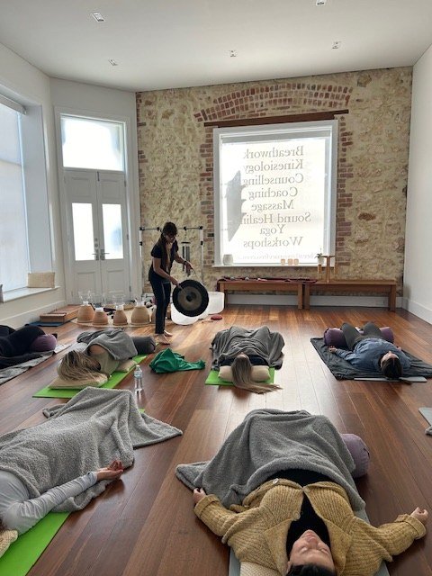 Participants lie under blankets facing Danielle and her instruments at Breathing Space.