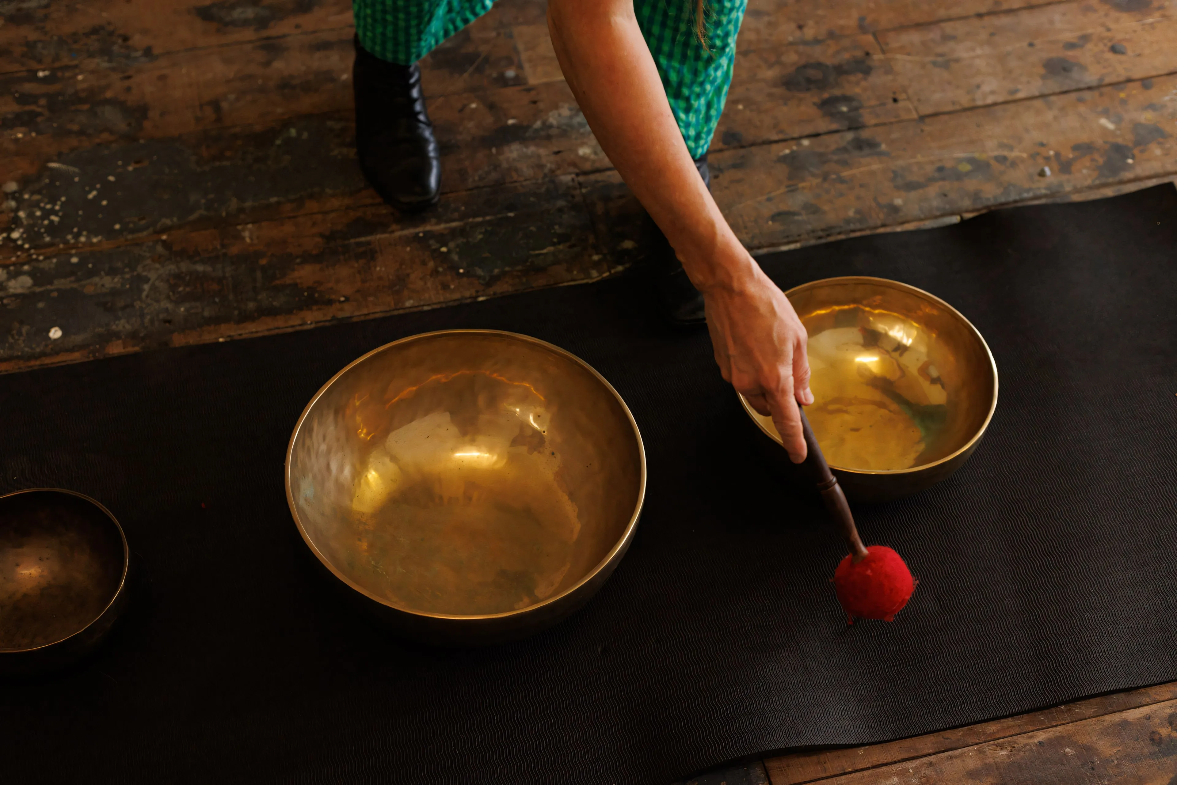 Danielle’s hand arranging brass singing bowls on a dark cloth.