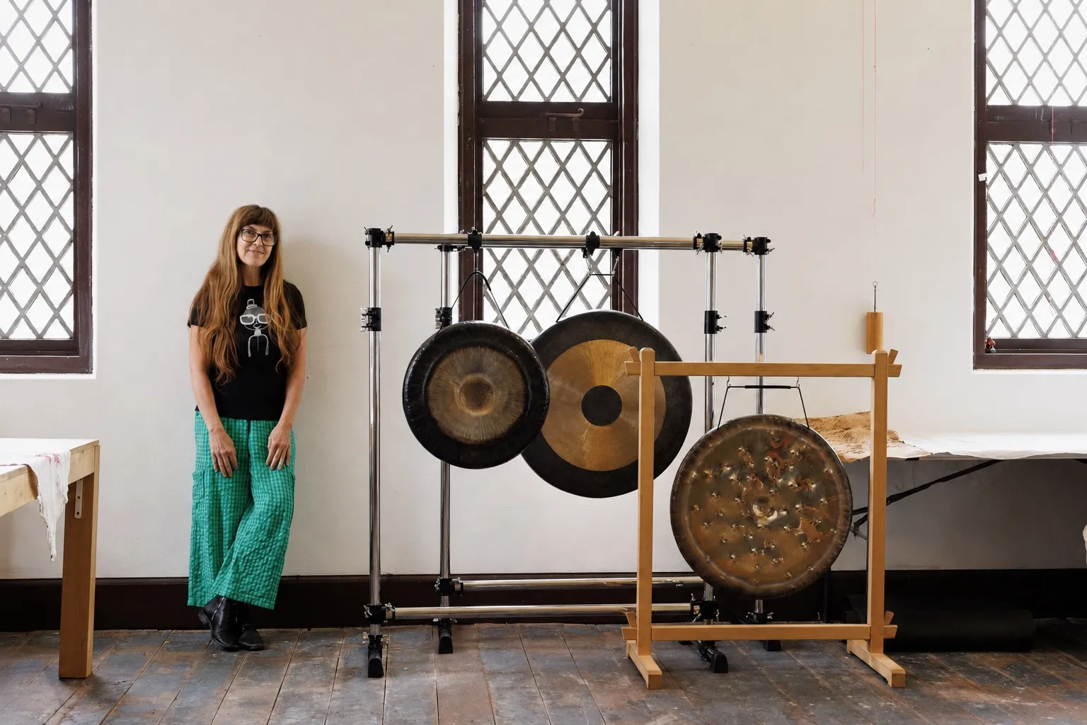 Danielle standing beside a set of large gongs in a bright studio.