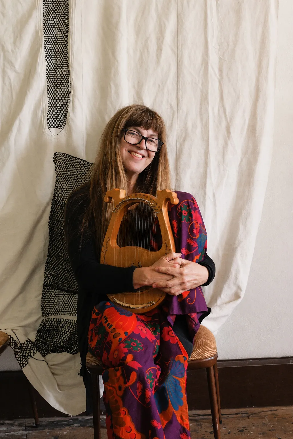Danielle smiling while holding a small wooden lyre.