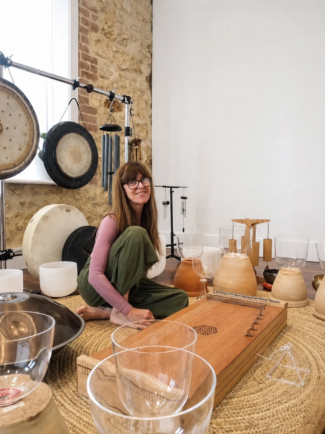 Danielle Joynt seated among gongs, singing bowls and a monochord.
