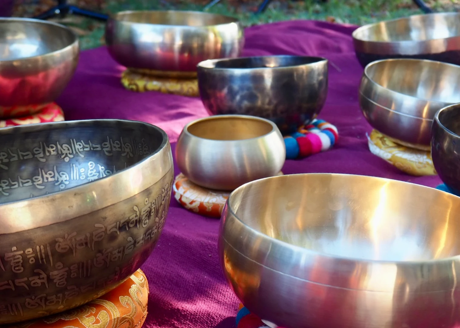 A collection of Tibetan singing bowls arranged on richly coloured fabric.