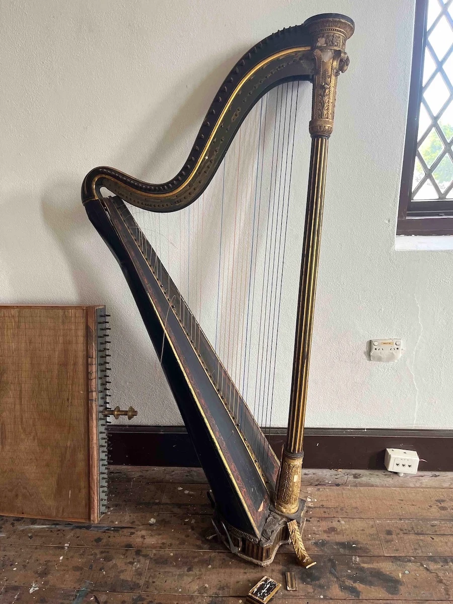 Full profile of the historic Érard harp, showing its curved neck, strings and decorated column.