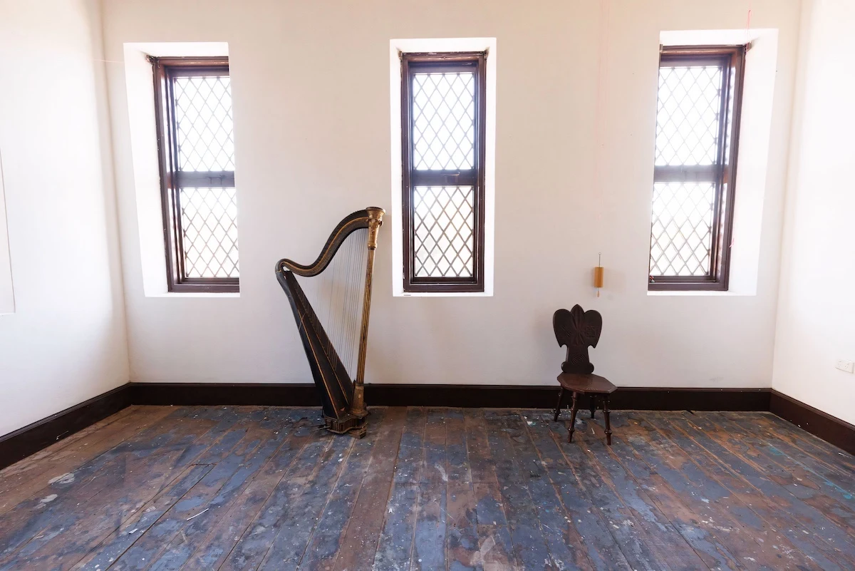An early nineteenth-century Érard harp standing in a quiet room between three tall windows.