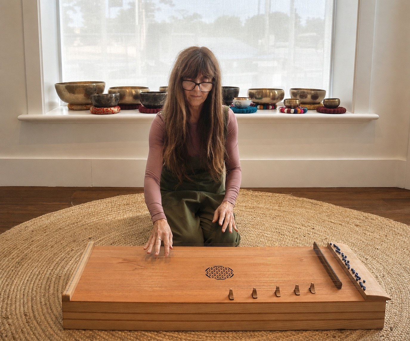Danielle Joynt seated at a monochord, with singing bowls arranged behind her.