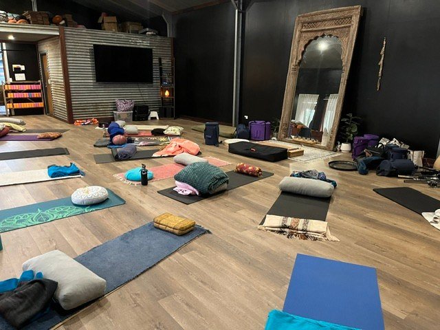 Mats and blankets arranged in a dark-walled studio at Premalaya.