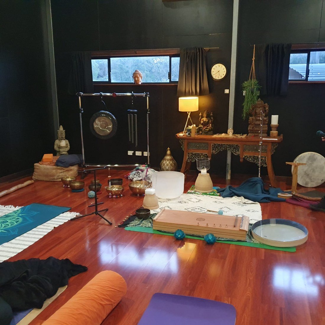 A monochord and bowls at the front of the studio with mats laid out for listeners.