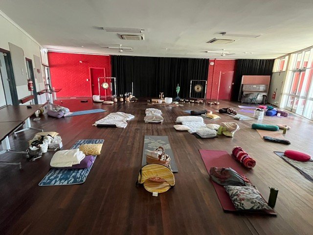 Mats, pillows and folded blankets arranged across a timber-floored retreat room.