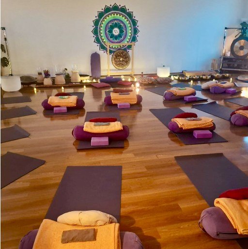 Purple mats, bolsters and folded blankets ready for a session beneath the Spanda mandala.
