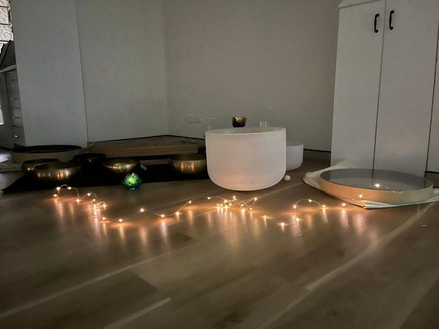 Singing bowls and a large white crystal bowl illuminated by a string of warm lights.