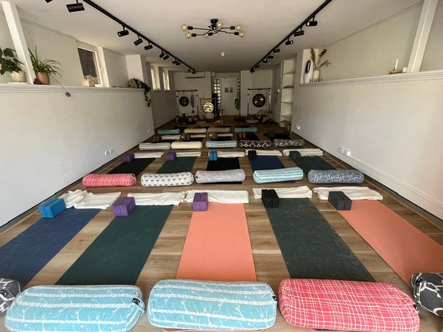 Rows of mats and folded blankets extend towards instruments in the long studio.